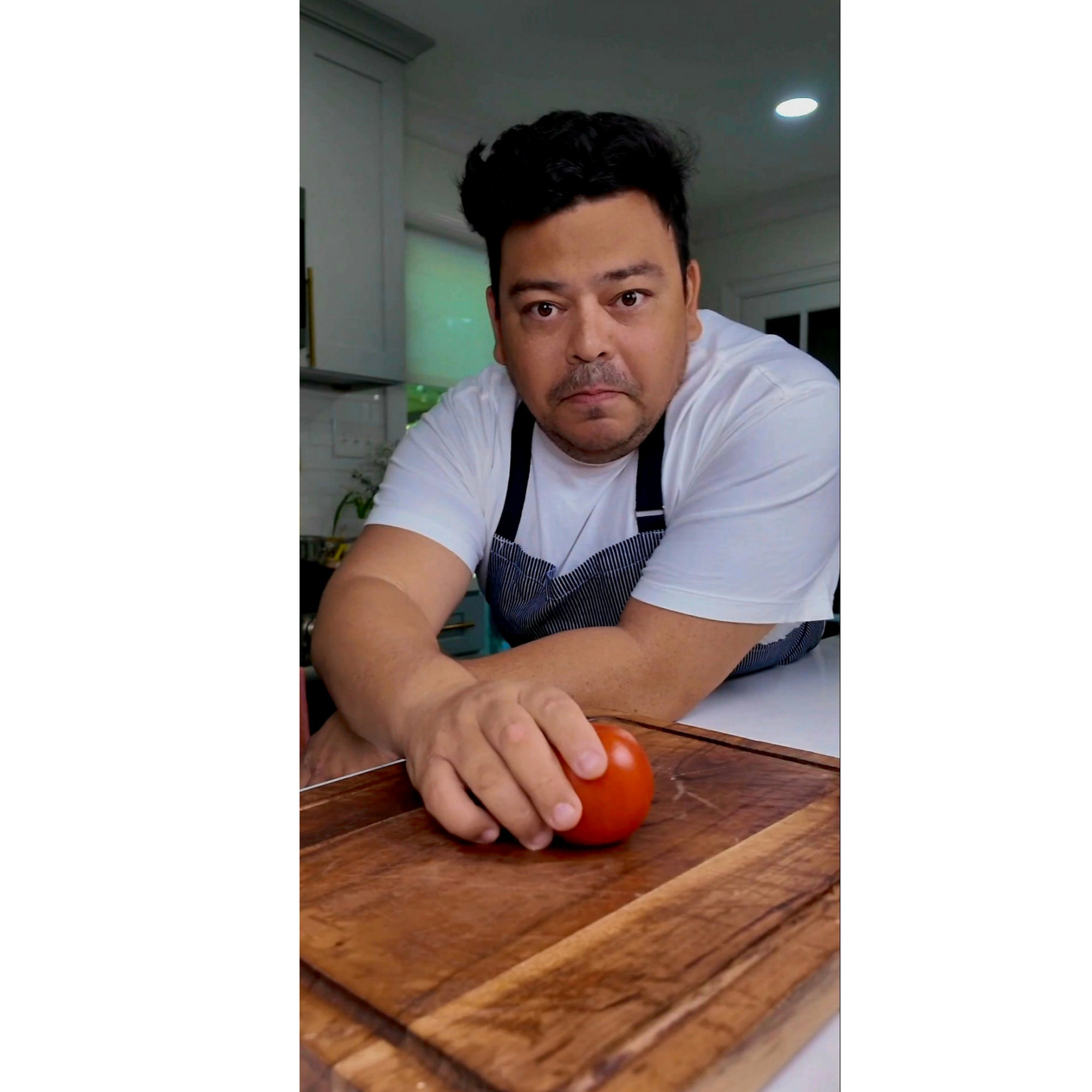 Portrait of Chef Julio Machado leaning on a wooden kitchen counter