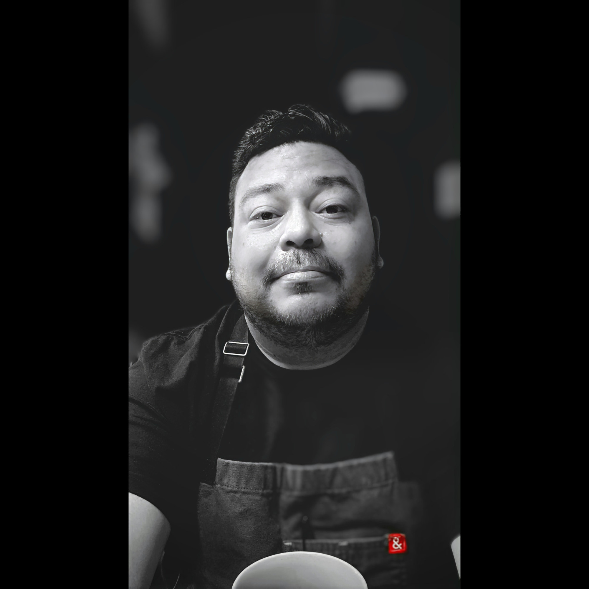 Black-and-white portrait of Chef Julio Machado wearing a chef apron