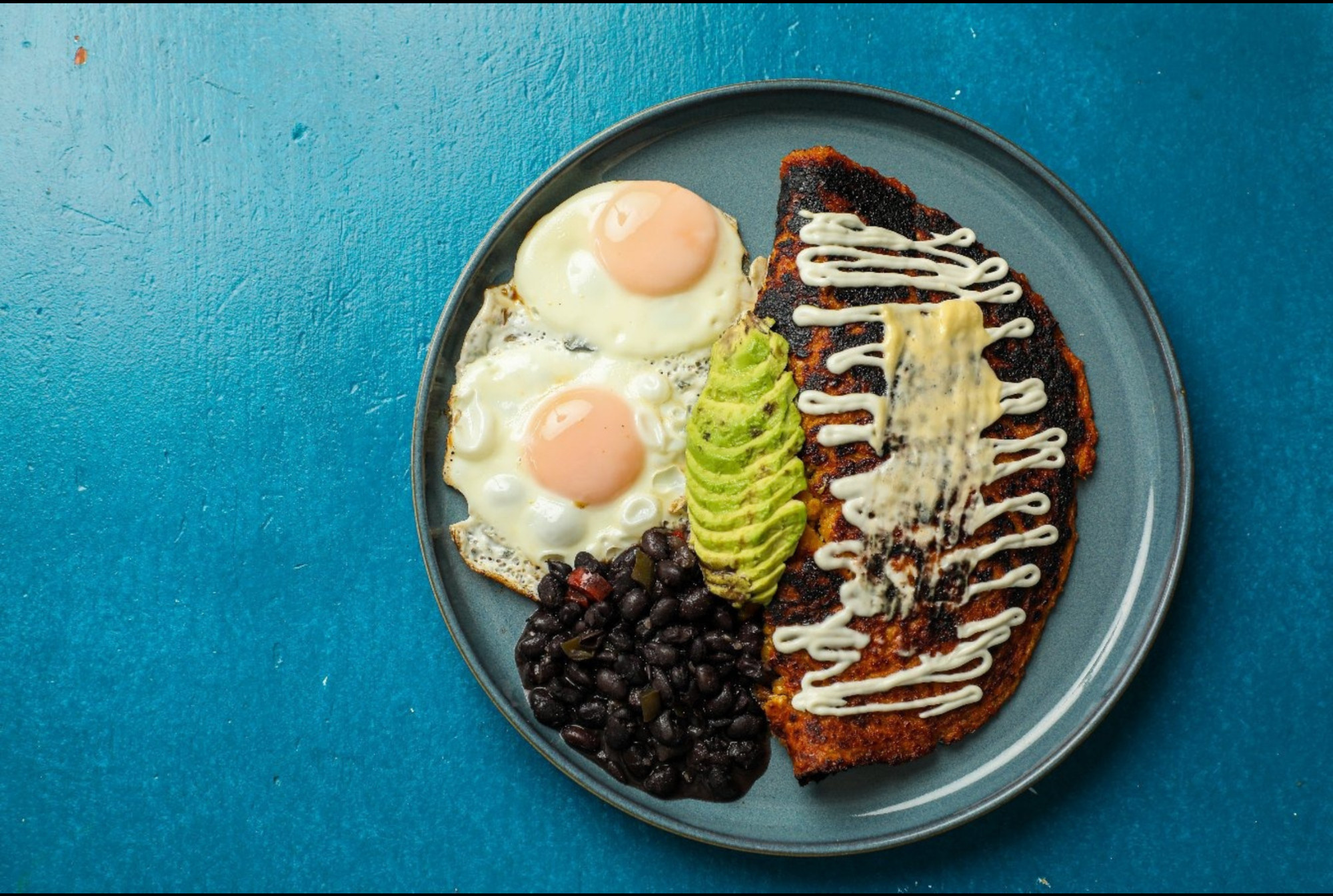 Overhead view of a colorful breakfast dish on a bright blue background