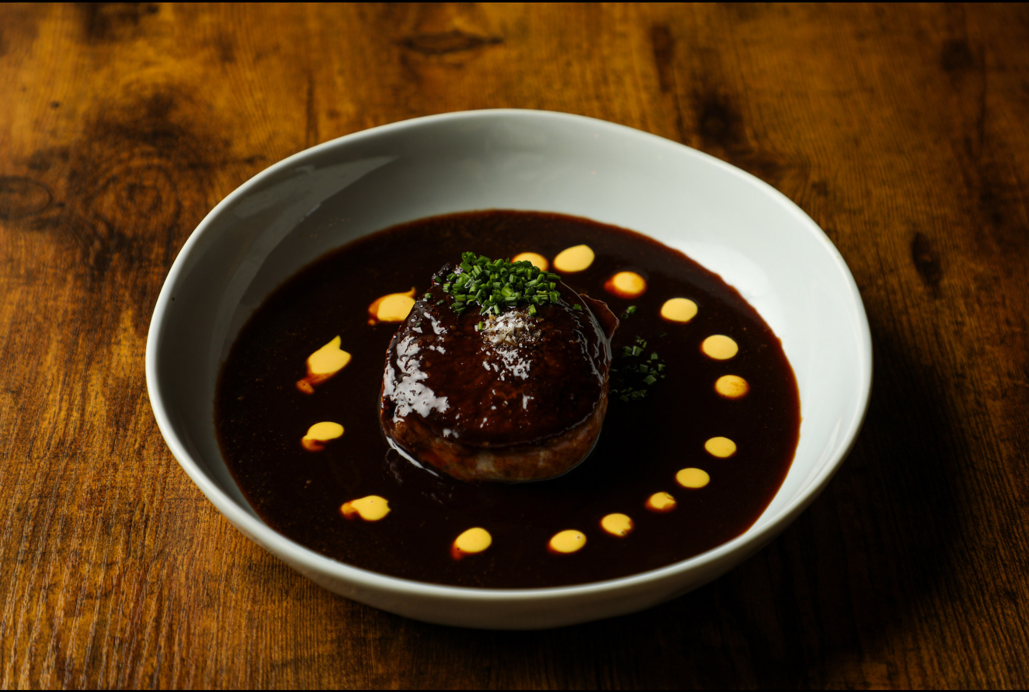 Dark glazed culinary creation plated in a white bowl, from Chef Julio Machado’s food portfolio